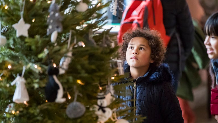 Child visitor looking at a Christmas tree in Sudbury Hall and the National Trust Museum of Childhood in Derbyshire